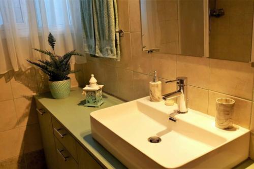 uma casa de banho com um lavatório branco e um espelho. em Villa Rania Loutraki em Loutraki