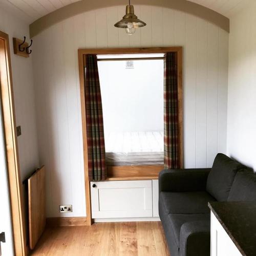 sala de estar con sofá y ventana en Astwell Mill Luxury Shepherds Hut, en Helmdon