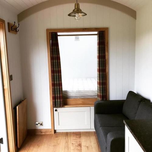 a living room with a couch and a window at Astwell Mill Luxury Shepherds Hut in Helmdon