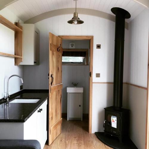 een keuken met een houtkachel in een kamer bij Astwell Mill Luxury Shepherds Hut in Helmdon