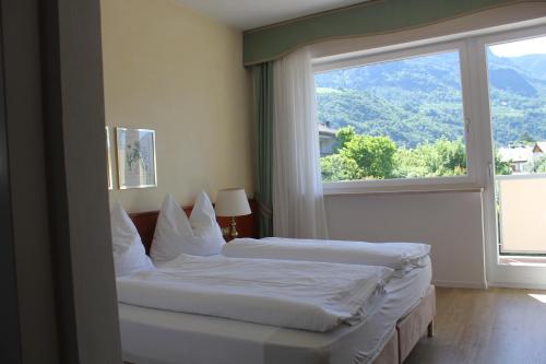 two beds in a room with a large window at Hotel Annabell in Merano