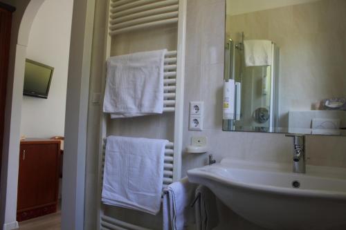 bagno con lavandino, specchio e asciugamani di Hotel Annabell a Merano