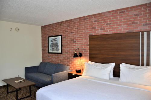 a hotel room with a bed and a chair at Burrstone Inn, an Ascend Collection Hotel in Utica