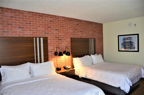 a hotel room with two beds and a brick wall at Burrstone Inn, an Ascend Collection Hotel in Utica
