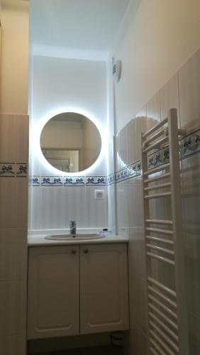 une salle de bain blanche avec un lavabo et un miroir dans l'établissement Appartement l'Estivalière face à la mer, à Wimereux