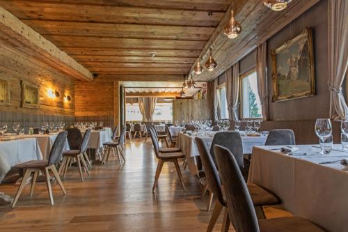 a dining room with tables and chairs and wooden ceilings at Dolomiti Lodge Alverà in Cortina dʼAmpezzo