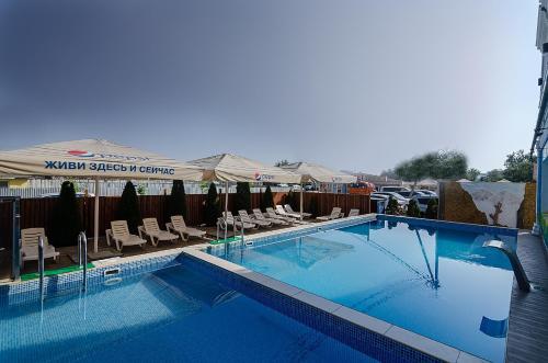 a large swimming pool with chairs and umbrellas at Золотой берег in Vityazevo