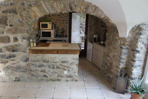 a kitchen with an archway in a stone wall at L'Attrape Rêve Insolite in Saint-Vincent-de-Barrès