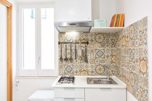 a kitchen with a sink and a tile wall at SorrentoVibes - Central Sorrento Apartment by PiazzaTasso&OldTown in Sorrento