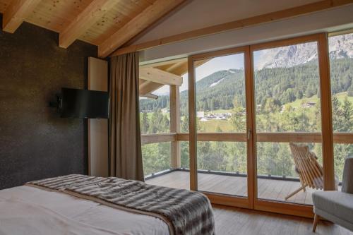 a bedroom with a bed and a large window at Dolomiti Lodge Alverà in Cortina dʼAmpezzo