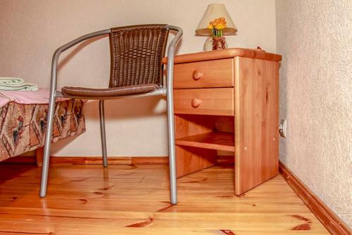 a chair next to a wooden dresser with a lamp at Pie Pifa in Pāvilosta
