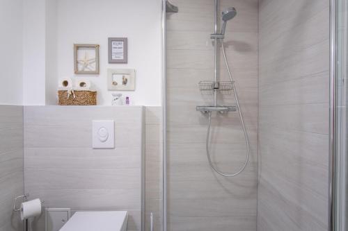 a bathroom with a shower with a glass door at A White Cliffside Studio in Pag