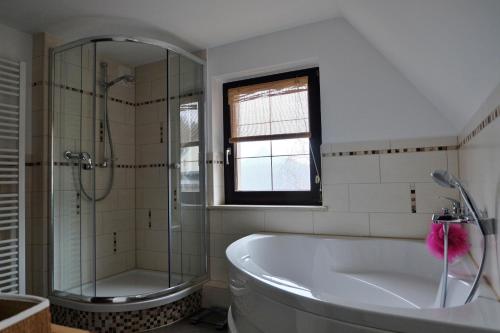 ein weißes Bad mit einer Badewanne und einer Dusche in der Unterkunft Doppelzimmer Liliensteinblick 1.OG in Bad Schandau