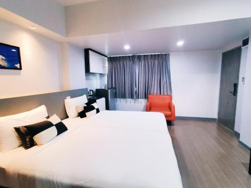 a hotel room with a large bed and a red chair at Star Sukhumvit in Bangkok