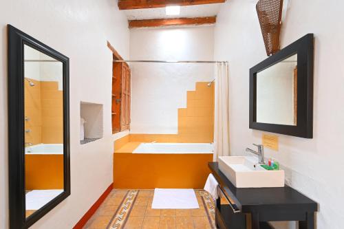 a bathroom with a tub and a sink and a mirror at Hotel Meson Cuevano in Guanajuato