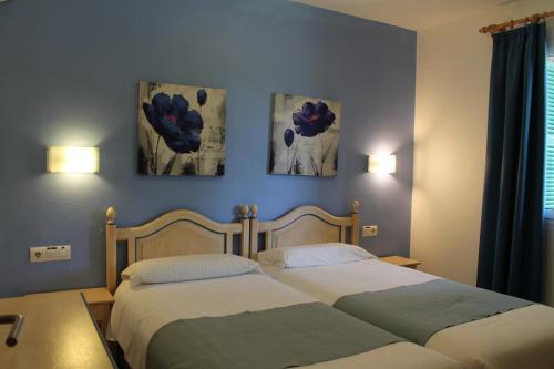 2 posti letto in una camera da letto con 3 dipinti alle pareti di Villa RAQUEL a Cala'n Forcat