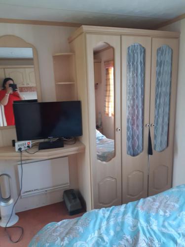 a bedroom with a bed and a tv and a mirror at Domek holenderski in Łuka