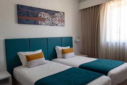 duas camas num quarto de hotel com azul e branco em Hotel Santa Cecília em Fátima