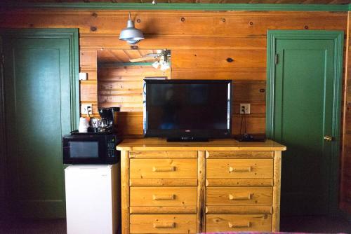 a television on a dresser in a kitchen with two doors at Shaver Lake Village Hotel in Shaver Lake