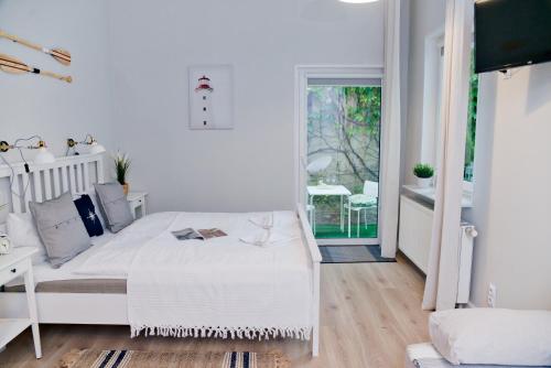a white bedroom with a bed and a window at Portofino Seaside Apartments in Międzyzdroje
