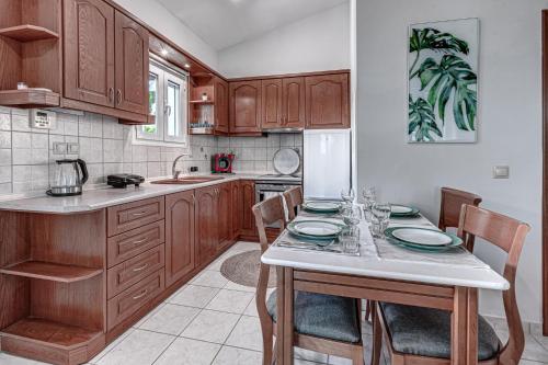 een keuken met houten kasten en een tafel met stoelen bij Dream Garden Apartments Corfu in Kommeno