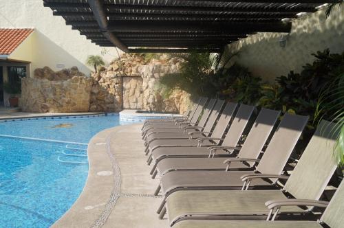 a row of chaise lounge chairs next to a swimming pool at Hotel Argento in Cuernavaca