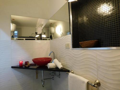 un bagno con una ciotola rossa su un bancone con specchio di Appartamento con piscina immersa nel verde a Cascina