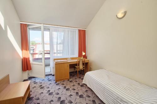 a bedroom with a bed and a desk and a window at Vila Kastytis in Nida