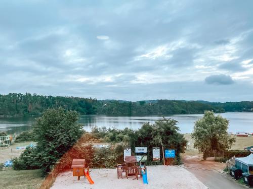 a view of a lake with tables and chairs at Chaty a Apartmány Hracholusky Kemp Kosatka in Pňovany