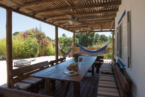 a wooden deck with a wooden table and benches at Casa da tertulia in Comporta