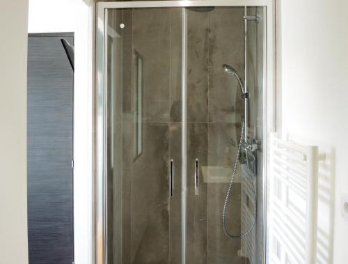 La salle de bains est pourvue d'une douche avec une porte en verre. dans l'établissement Les Chambres du Verger, à Amiens