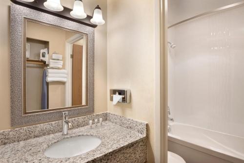 a bathroom with a sink and a mirror and a tub at Days Inn by Wyndham Nanaimo in Nanaimo