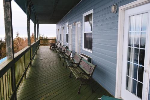 a porch with benches on a blue house at Inn at the Cape 