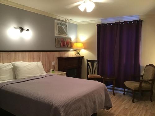 a bedroom with a bed and purple curtains at Petit Hôtel Amara in La Malbaie
