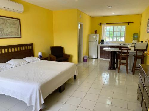 a bedroom with a bed and a kitchen with yellow walls at Casa Coral Cozumel in Cozumel