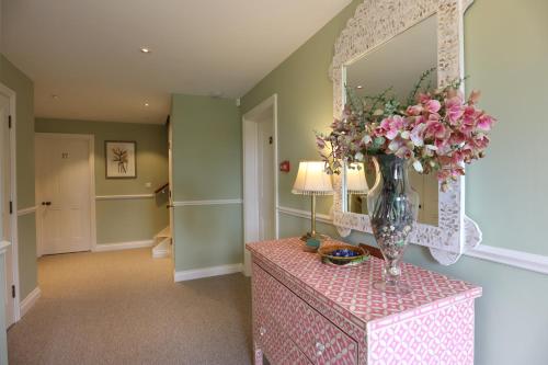a vase of flowers on a table with a mirror at Tyndall Villa Boutique B&B in Bath