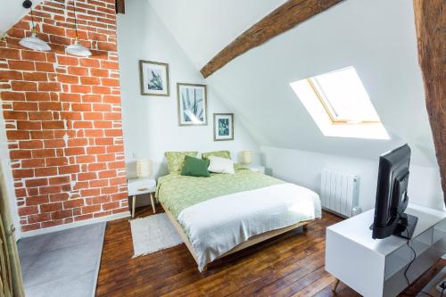 a bedroom with a bed and a brick wall at Au Zen Garden in Auxerre