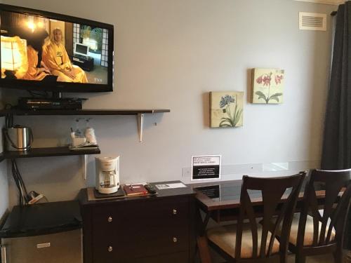 a living room with a table and a tv on the wall at Petit Hôtel Amara in La Malbaie