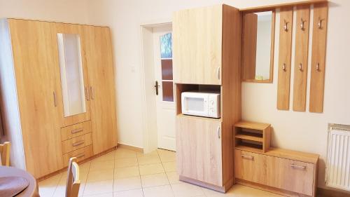 a kitchen with wooden cabinets and a microwave at APARTMÁNY POD ČERCHOVEM in Trhanov