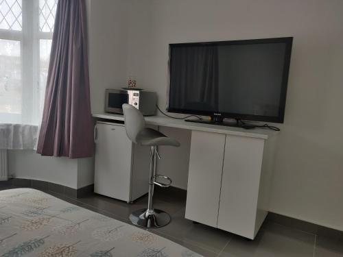Zimmer mit einem Schreibtisch, einem TV und einem Stuhl in der Unterkunft Stunning Double Room in Harrow Wembley - Khoob House in London