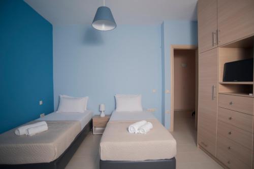 two twin beds in a room with a tv at Elina's Maisonette in Episkopos