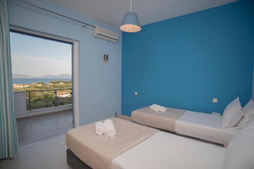 two beds in a room with a large window at Elina's Maisonette in Episkopos