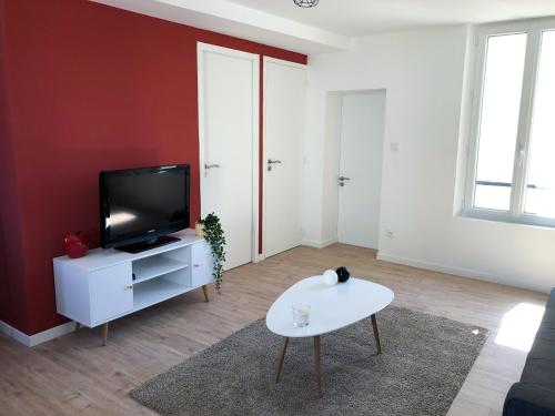 a living room with a tv and a white table at Une parenthèse de confort à proximité du centre in Saumur