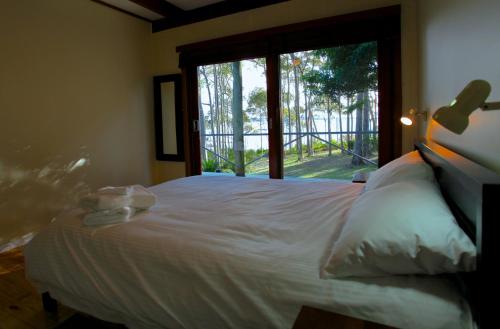 a bedroom with a white bed with a large window at Beachgum in Sunshine Bay
