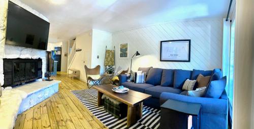 Red River Getaway- Ski In Ski Out, Newly Remodeled في ريد ريفر: غرفة معيشة مع أريكة زرقاء ومدفأة
