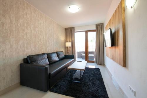 ein Wohnzimmer mit einer schwarzen Ledercouch und einem Tisch in der Unterkunft Rezidence Tři Studně in Tři Studně