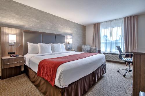 
a hotel room with a bed, chair, desk and a television at Comfort Inn & Suites South in Calgary
