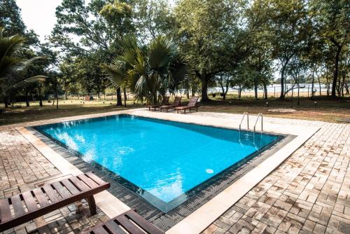 - une piscine avec 2 bancs à côté d'un parc dans l'établissement Tranquil Wild, à Tanamalwila