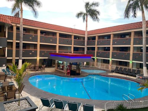 uma piscina em frente a um hotel com palmeiras em Hotel La Finca em Hermosillo