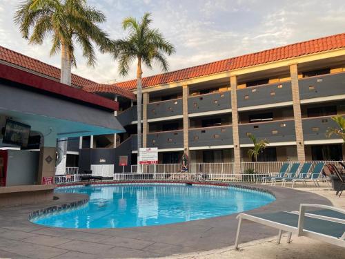 a swimming pool in front of a building with palm trees at Hotel La Finca in Hermosillo
